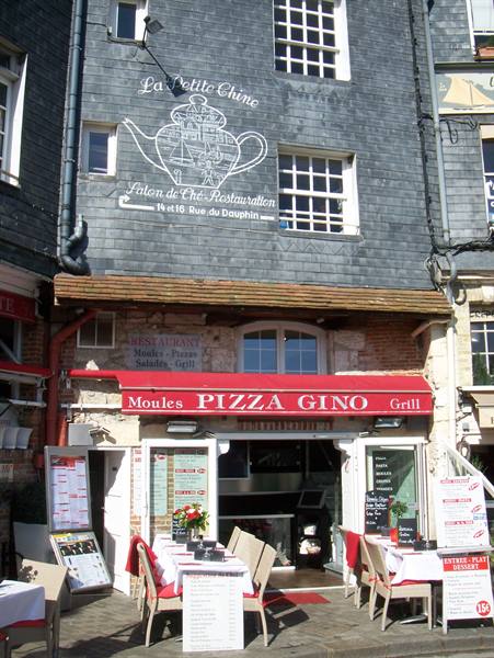 Pizza Gino restaurant with set tables under red awning, slate facade