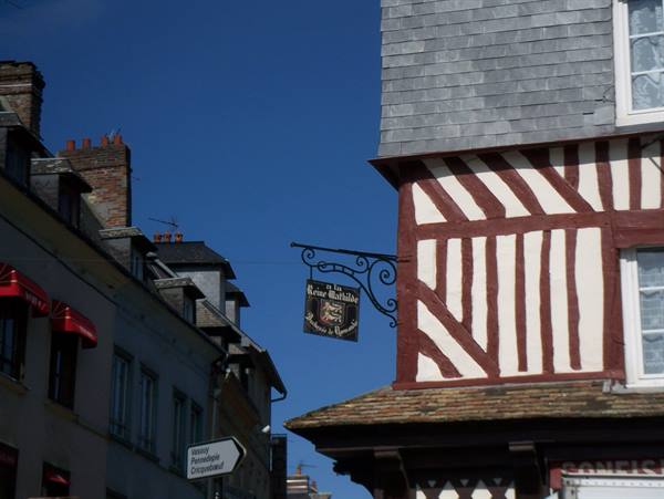 Red and white half-timbered house with wrought iron sign in Honfleur
