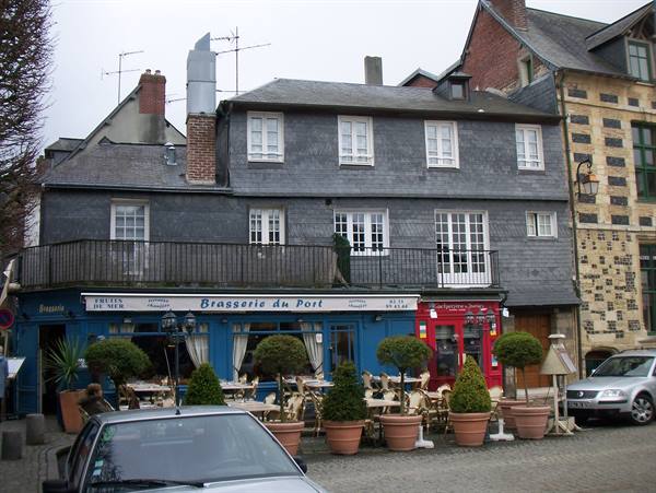 Brasserie du Port with terrace and potted boxwoods, blue facade under slate houses