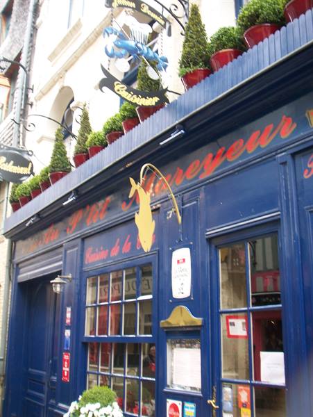 Blue facade of Le Petit Mareyeur restaurant with boxwood planters