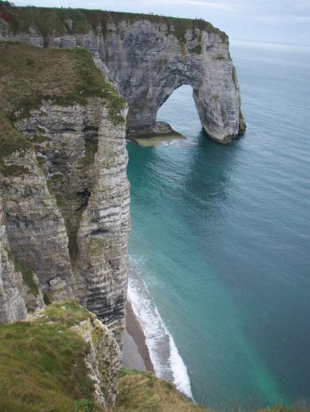 Limestone cliff with natural arch over turquoise sea, beach below, Étretat