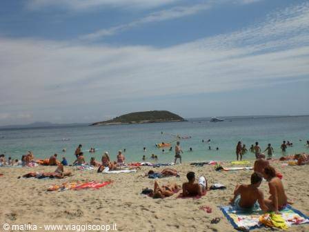 Beachgoers on pale sand, island in background, Cyprus sea