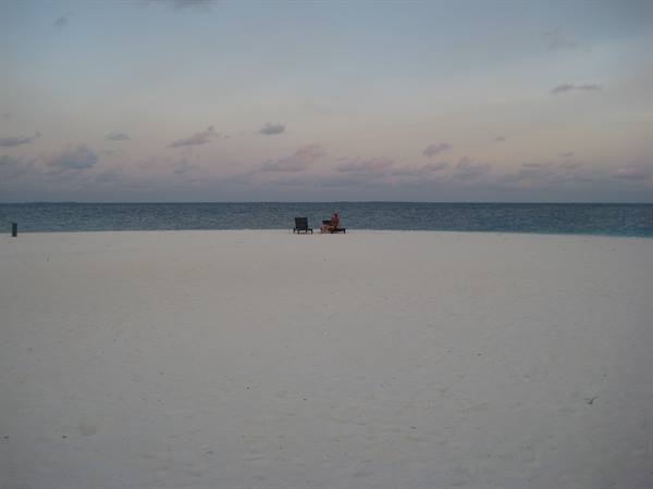 White sand beach with two lounge chairs facing the calm sea