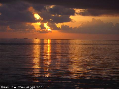 Sun breaking through clouds over the ocean, golden reflections on calm water