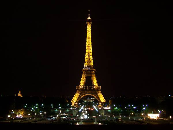 Golden-lit Eiffel Tower at night, lights and fountains below