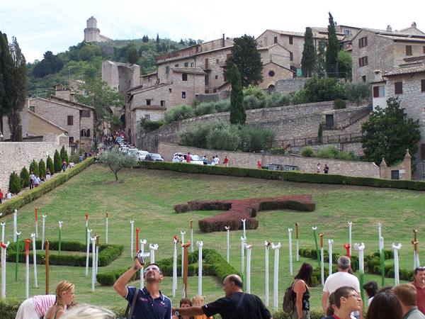 Tourists in the park beneath Assisi's stone houses, fortress on the hill