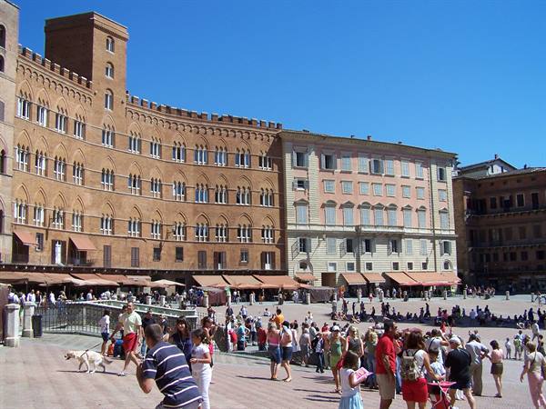 Tourists stroll across Siena's Piazza del Campo among medieval brick buildings