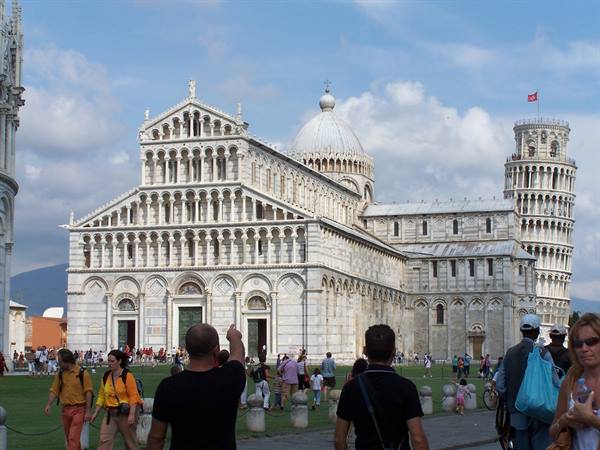 Tourists walking in front of Pisa Cathedral and the Leaning Tower