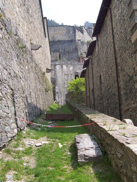 Grassy passage between stone walls at Forte di Bard