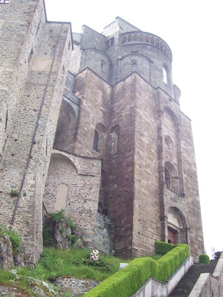 Sacra di San Michele: massive Romanesque stone apse under a grey sky