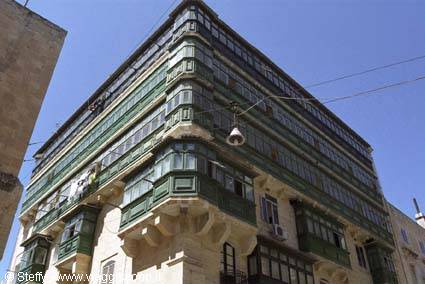 Limestone building with green wooden balconies in Valletta