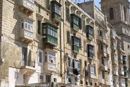 Limestone facades with enclosed wooden balconies and bell tower in Valletta