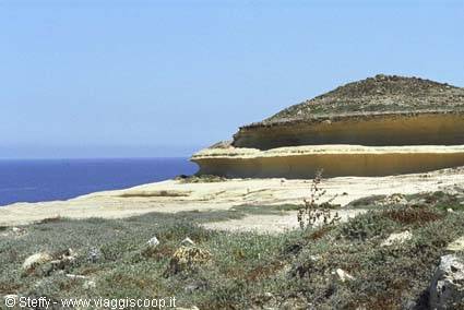 Layered limestone plateau above the blue sea, Mediterranean shrubs in front