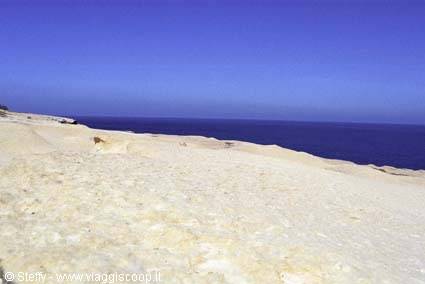White limestone rocky cliffs overlooking deep blue sea under clear sky