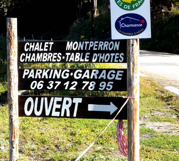 Wooden sign for Chalet Montperron with Ouvert arrow, beside the road