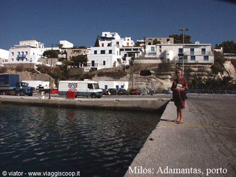 Tourist on the dock of Adamantas port in Milos, white houses in background