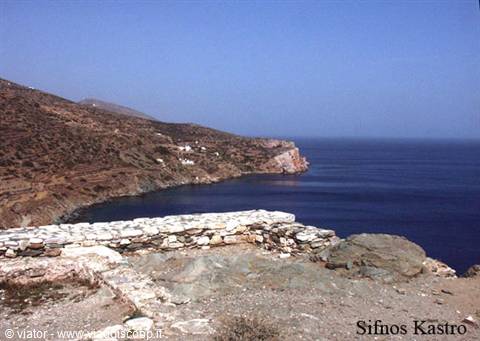 Ancient stone wall at Sifnos Kastro above dark bay and arid hills