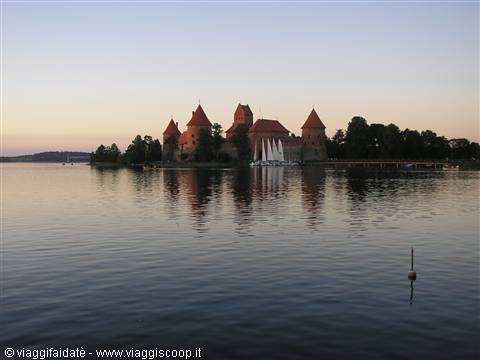 Trakai Island Castle reflected on the lake at dusk, sailboats nearby