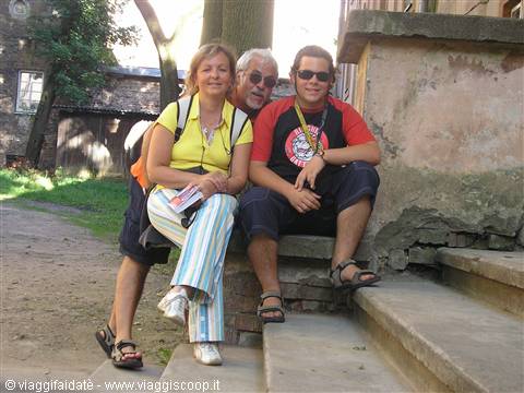 Tourists wearing sunglasses sitting on stone steps beside a crumbling old building