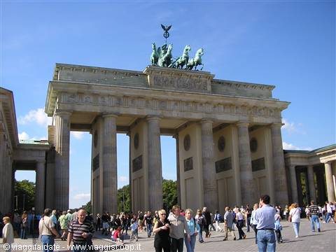 Tourists stroll beneath the stone columns of the Brandenburg Gate in Berlin