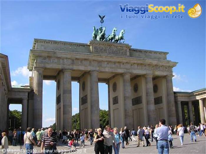 Tourists stroll beneath the stone columns of the Brandenburg Gate in Berlin