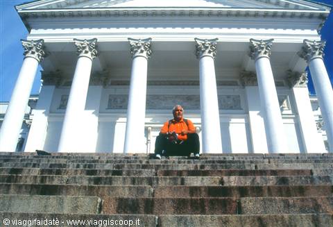 Tourist sitting on granite steps of Helsinki's white cathedral