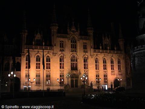 Illuminated Gothic facade at night in Bruges, lampposts in front of the building