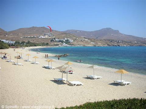 Sandy beach with straw umbrellas and sunbeds, red kite over the hills