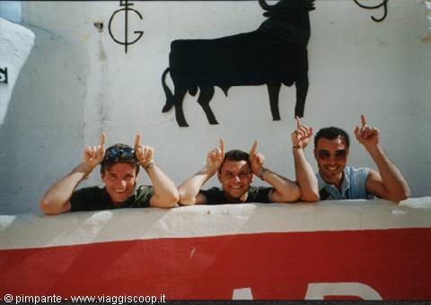 Three friends making bull horns under a black bull mural