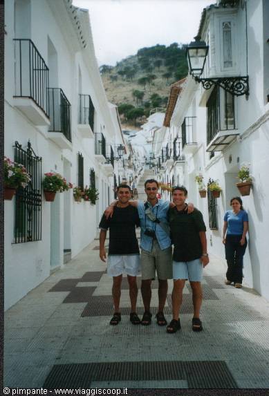 Three friends posing in a whitewashed Mijas alley, hanging flower pots