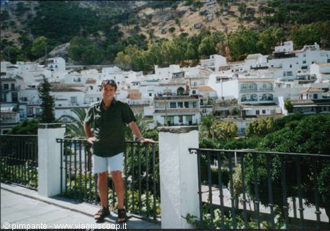 Man leaning on railing in front of whitewashed houses of Mijas