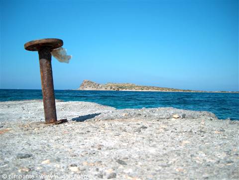 rusted mooring bollard on stone pier facing a small island