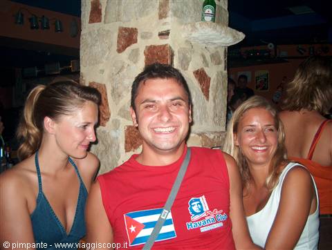 Smiling guy in red Habana Club t-shirt between two friends at a bar