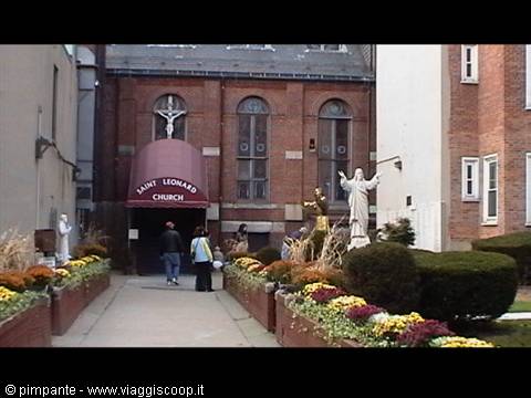 Saint Leonard Church entrance with statue and autumn flowers