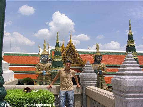 Tourist beside yaksha statues and golden roofs of Wat Phra Kaew, Bangkok