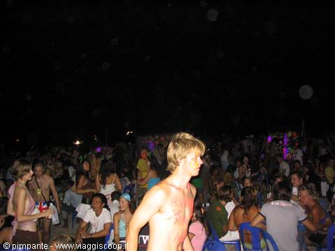 Night beach party, young people standing among blue plastic chairs