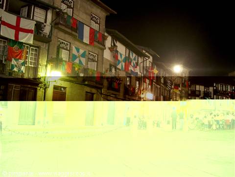 Stone buildings with district flags on balconies during Guimarães night festival