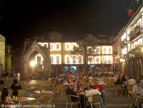 Crowded square in Guimarães at night, outdoor café tables under illuminated buildings