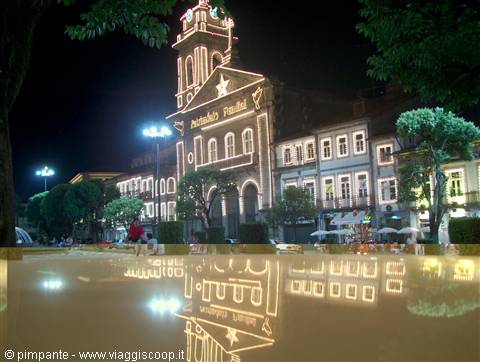 Illuminated church at night with Christmas lights, reflection on wet surface