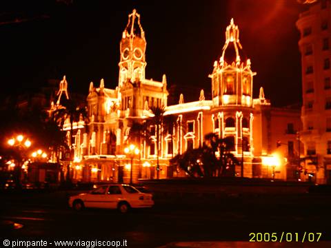 Malaga city hall lit up at night, a car passing by