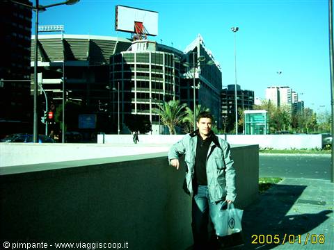Young man with bag leaning on a wall in front of Bernabéu stadium