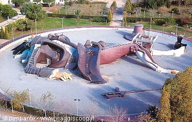 Giant lying Gulliver sculpture with children's slides in a green park