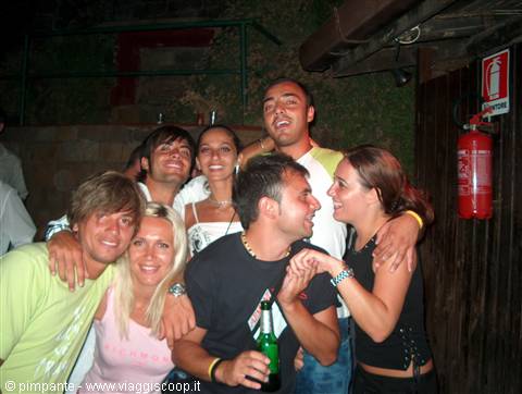 Group of smiling friends with beer bottle outside a nightclub