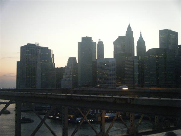 Manhattan skyscrapers at dusk seen from Brooklyn Bridge cables