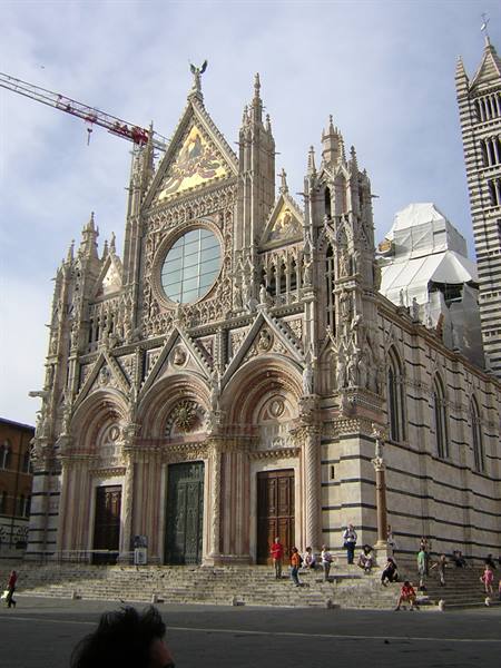 Gothic facade of Siena Cathedral in striped marble, tourists on the steps
