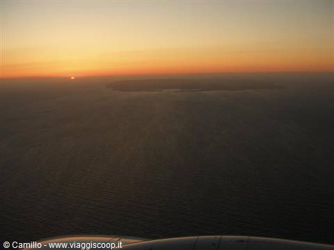 Island in the sea at dusk, photographed from the airplane window