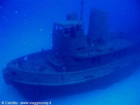 Sunken tugboat wreck underwater in deep blue light