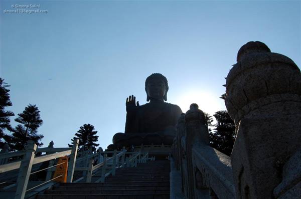 Great bronze Buddha silhouetted against the sun, stone stairs and railings, Tian Tan