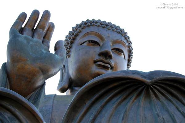 The bronze Big Buddha of Ngong Ping raises his hand against white sky