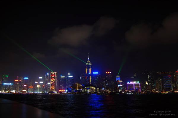 Hong Kong skyline at night with lit skyscrapers and green lasers over the harbour